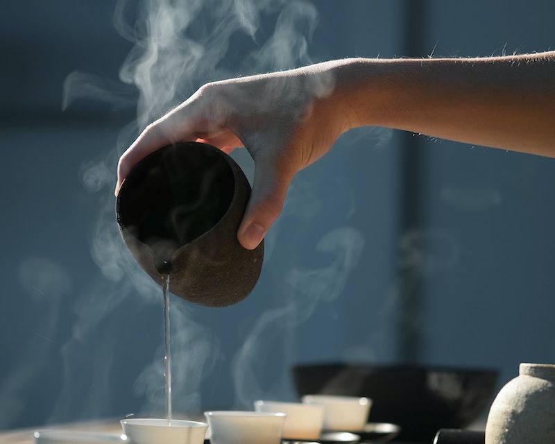 person pouring hot water on white cup